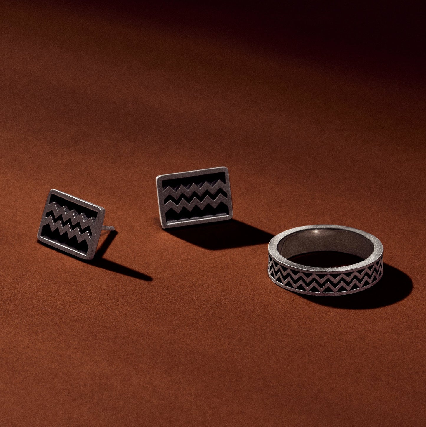 Silver ring jewelry collection with the ring and matching earrings inspired by Maya Hieroglyphs with satin oxidized finish on an earthy terracotta background